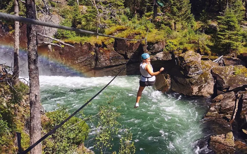 a woman crossing a river on a zipline