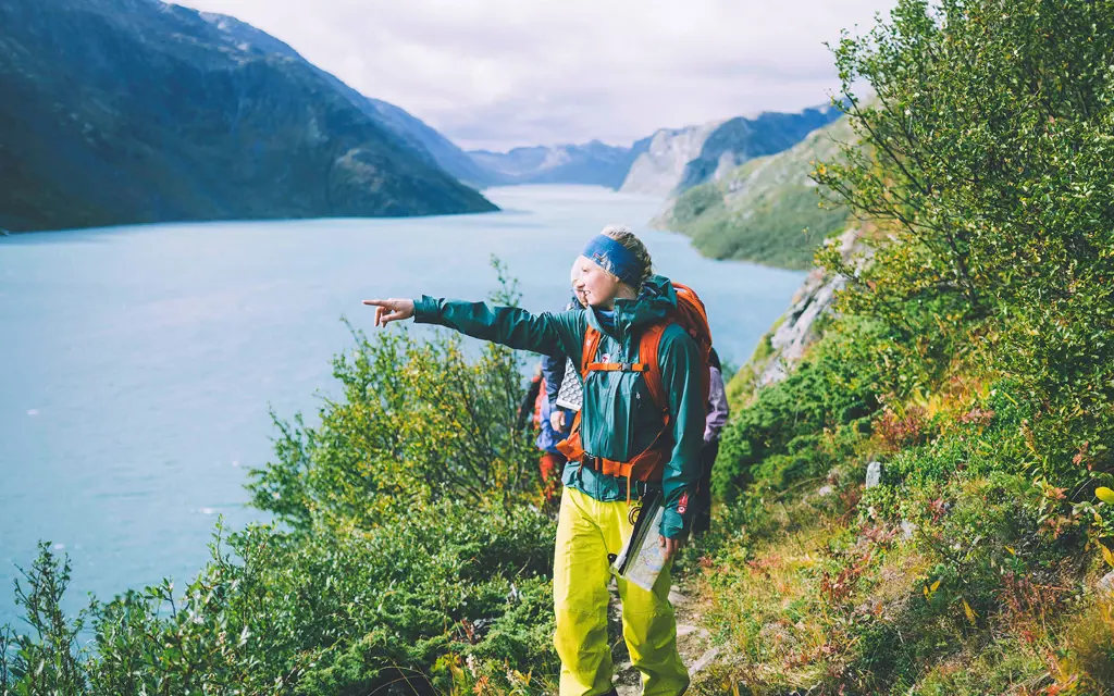 Two mountain hikers are walking on a path by a lake