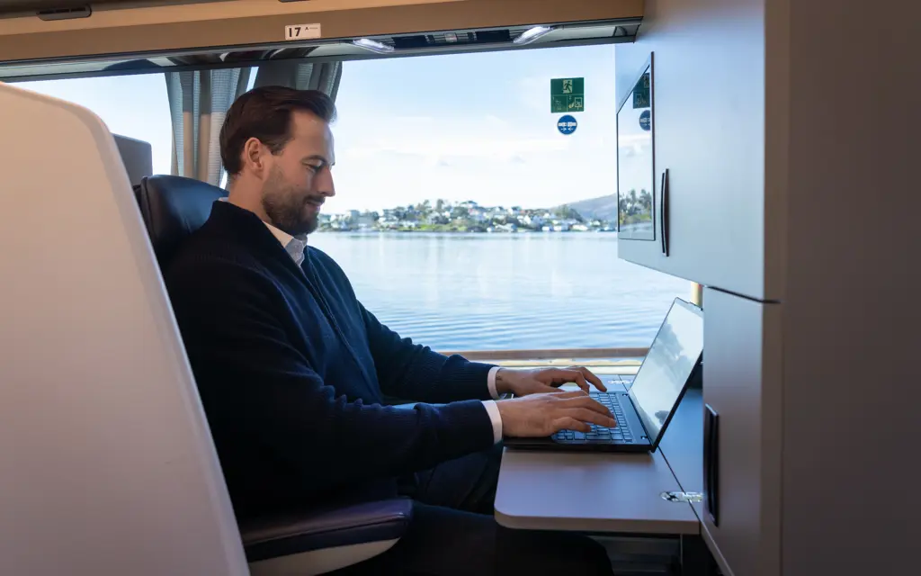 Mann jobber på laptop på kontorplass på buss