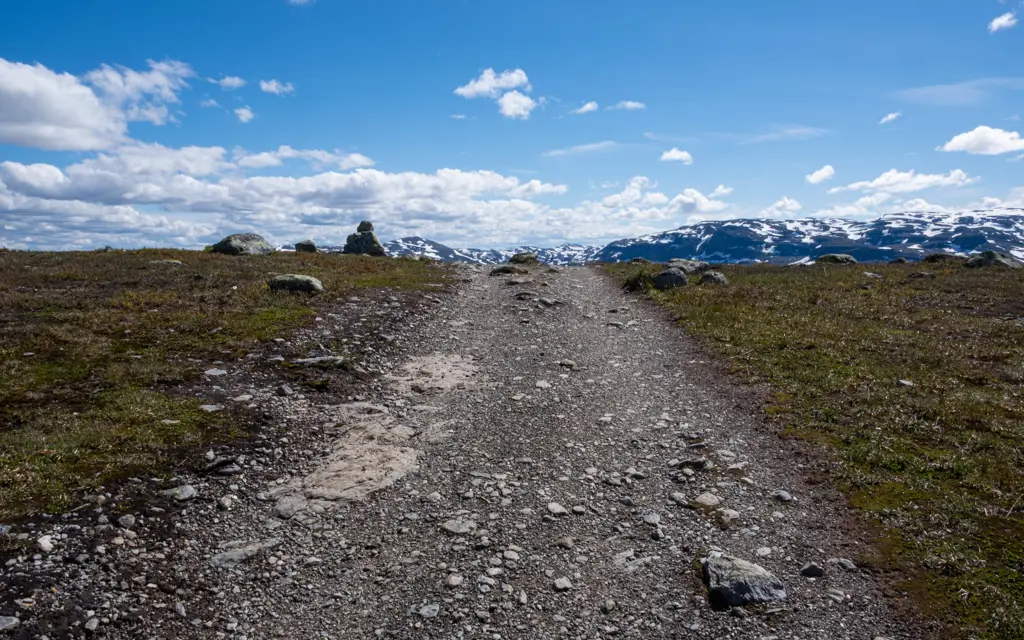 en gangvei somgår oppover, med fjellheimen i bakgrunnen og blå himmel med skyer over