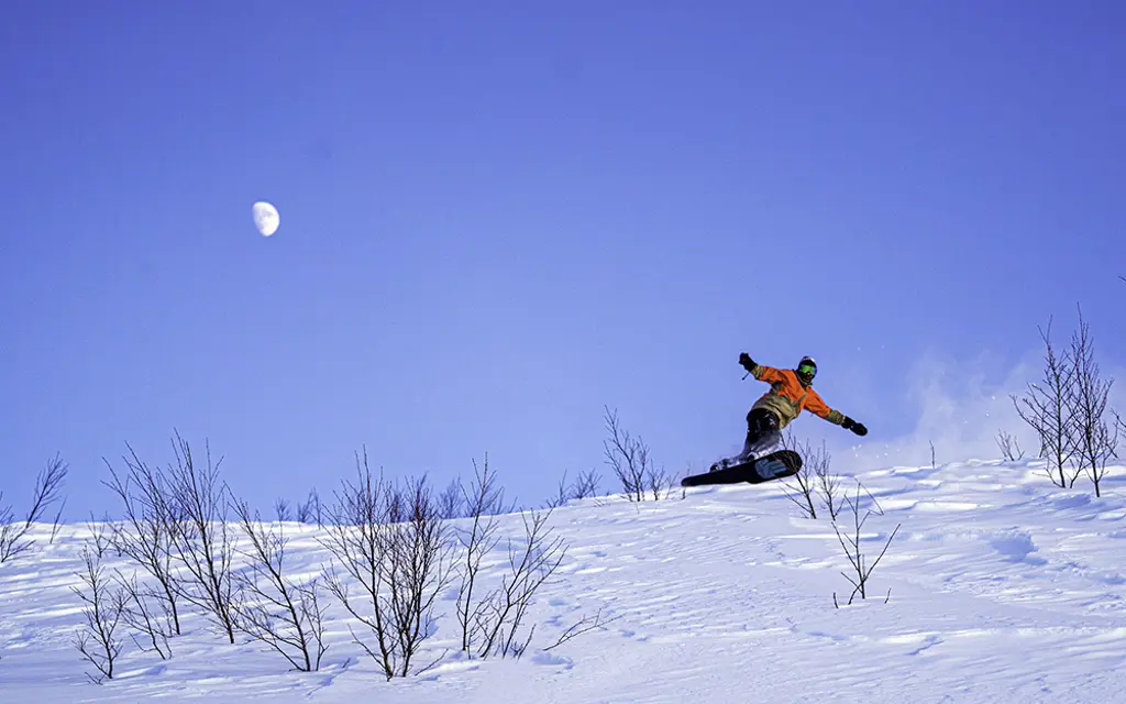 Snowboardkjører på vei ned fjellsiden