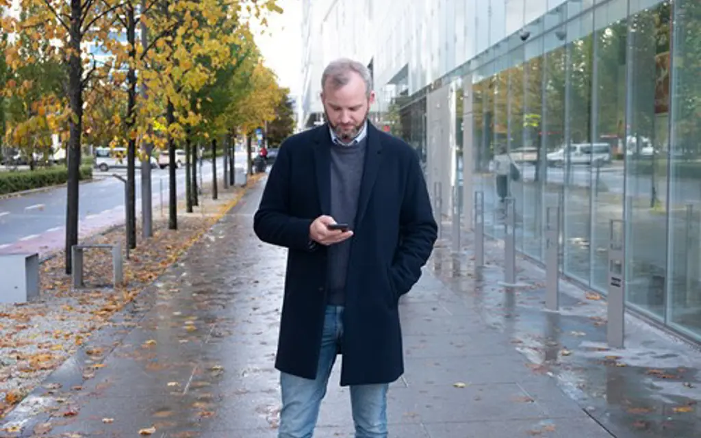 Mann sjekker billett på mobil