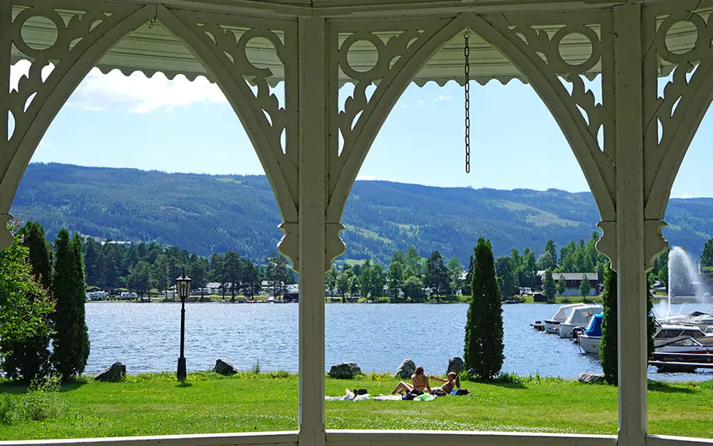 A seascape and mountain landscape are seen through arched house pillars on a white house.