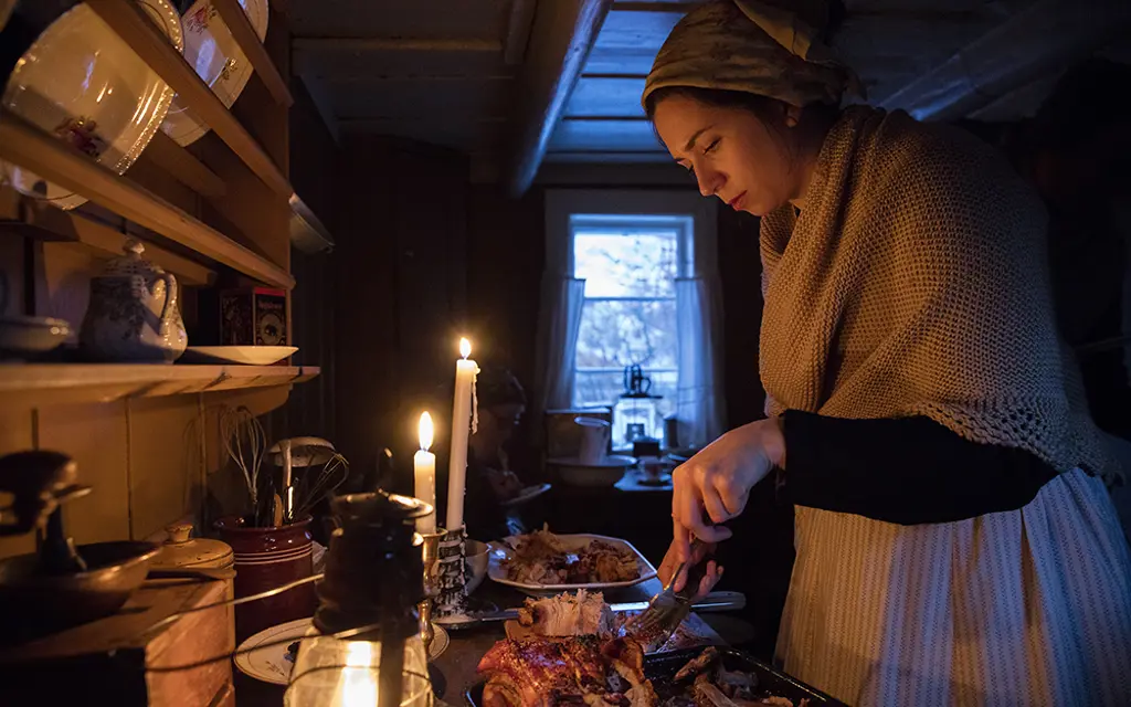 Kvinne tilbereder julemat i gammelt hus på Norsk folkemuseum