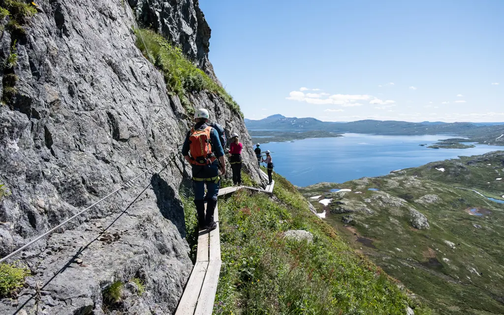 Fjellturister går Via Ferrata opp fjellsiden på Synshorn