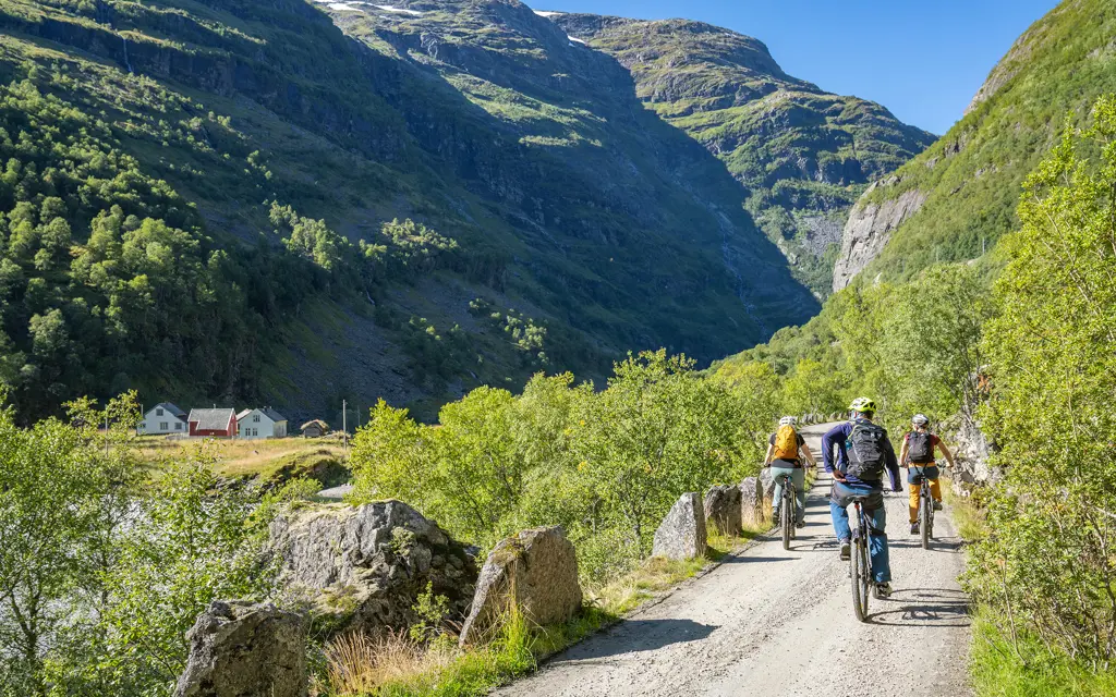 Tre syklister på grusvei i vakkert fjellandskap