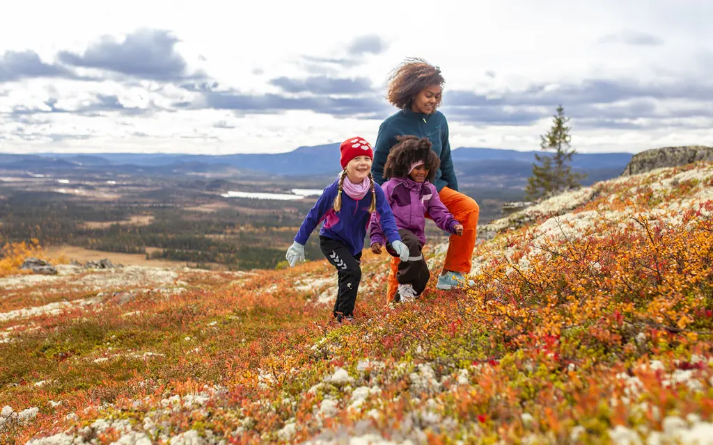 Kvinne og to barn går på tur i nydelige høstfarger i fjellet