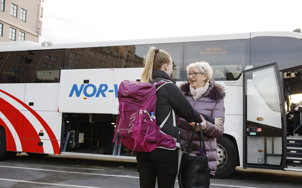 Ung kvinne og eldre kvinne møter hverandre utenfor buss