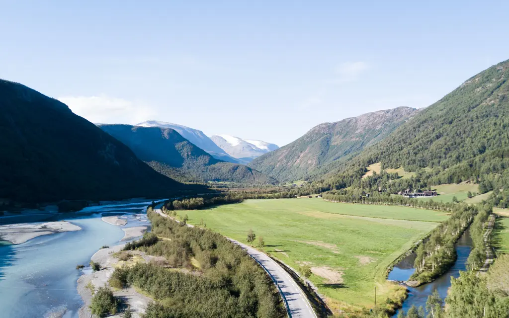 Vakkert landskap med fjell, grønne enger og blå elv