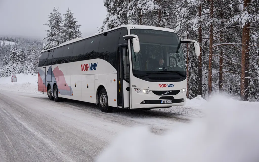 En buss fra NOR-WAY på en vei med mye snø rundt