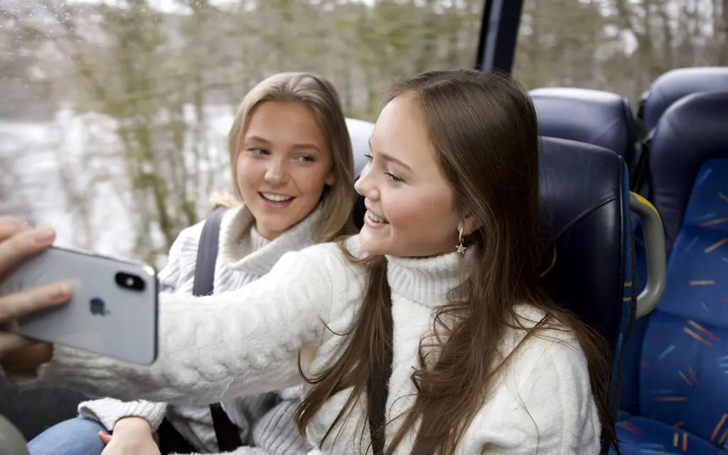 To jenter sitter på buss og tar selfie