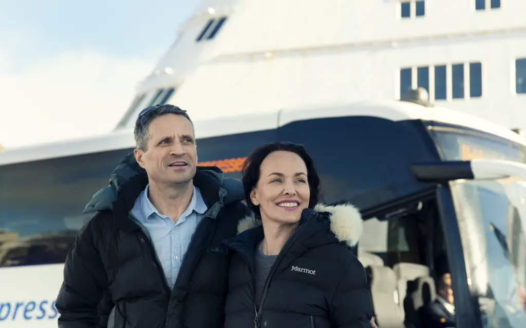 Happy couple in front of bus and DFDS ferry
