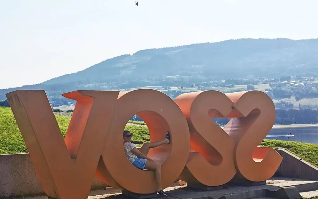 A huge sign spelling VOSS and the village and a paraglider in the background