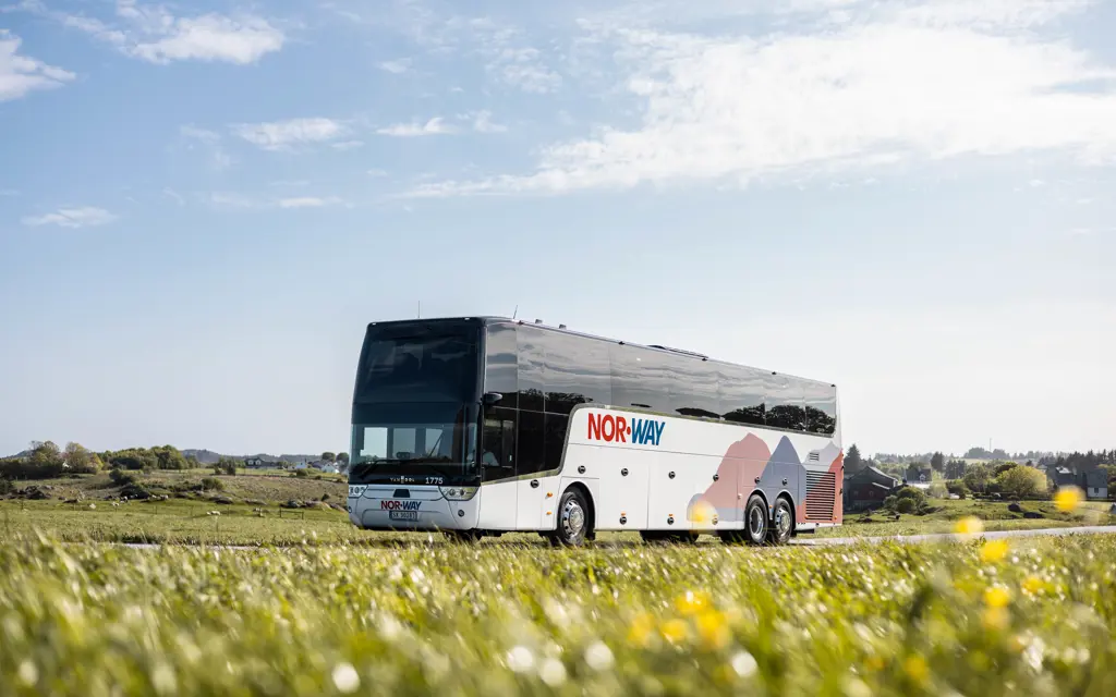 Buss kjørende på vei i sommerlandskap