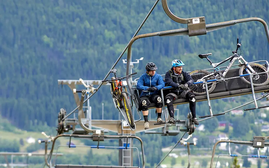 People on a ski lift with bikes and bike helmets during the summer in Trysil