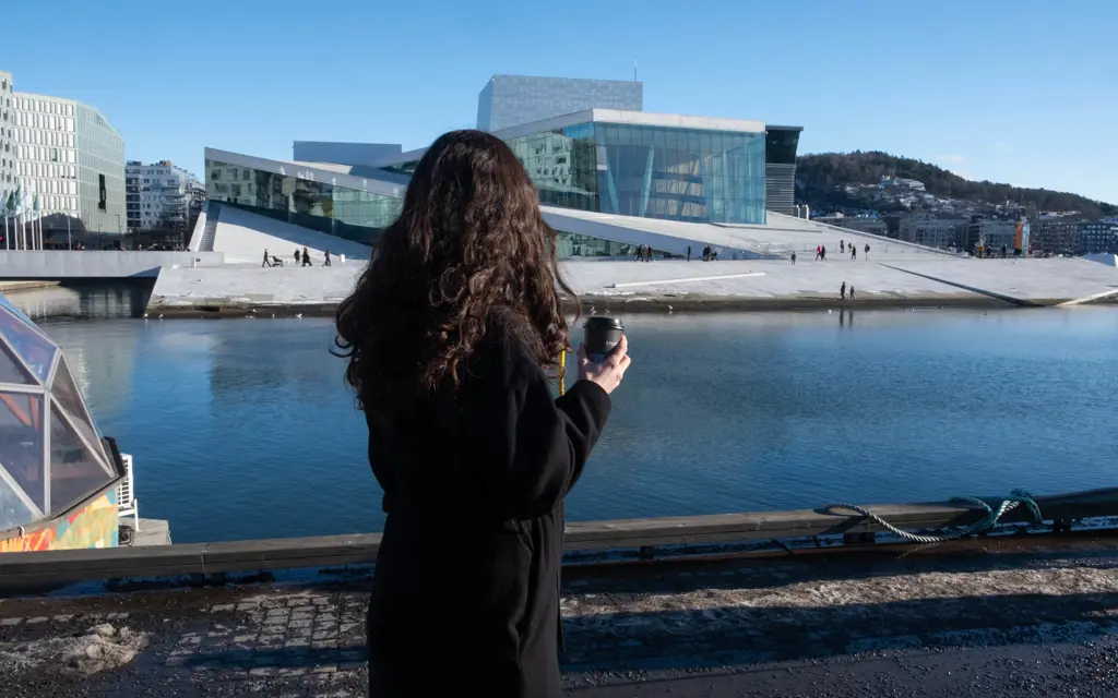 Person som med kaffe som ser til Operaen i Oslo