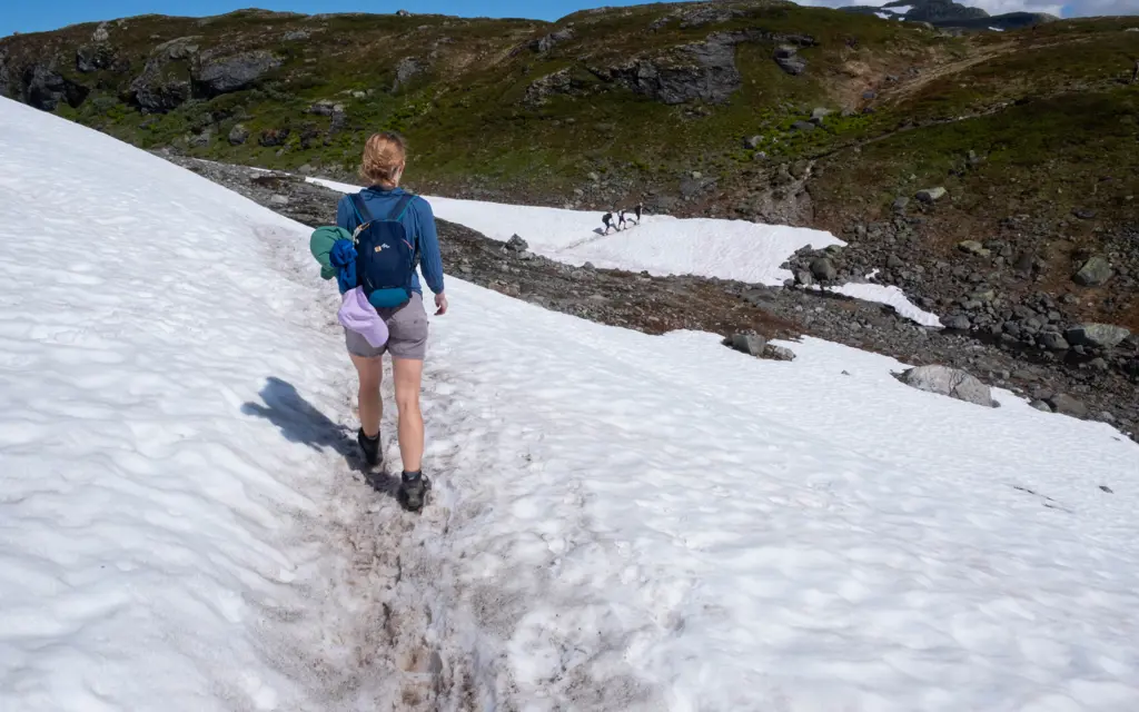 person går over snøfelt i fjellet