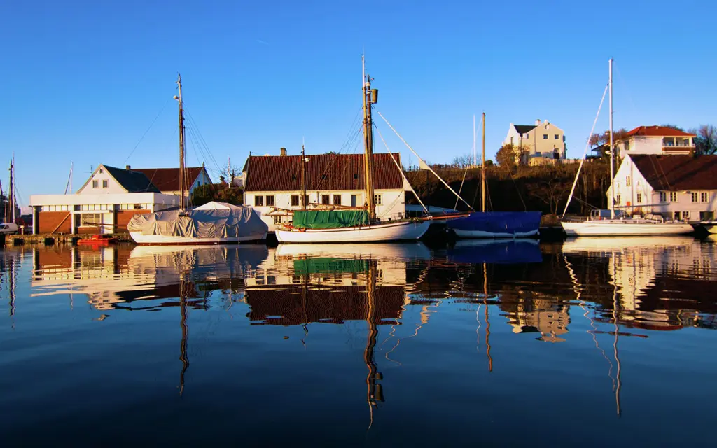 White wooden houses on the harbour with boats and water reflections