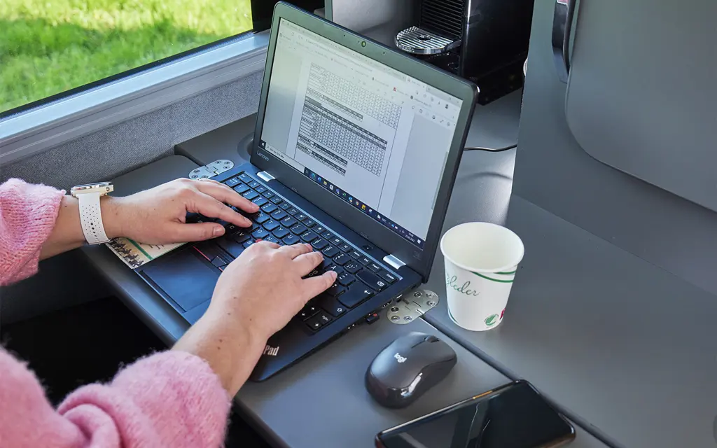 Book your own mobile work-zone: a computer and a cup of coffee at the desk in the bus
