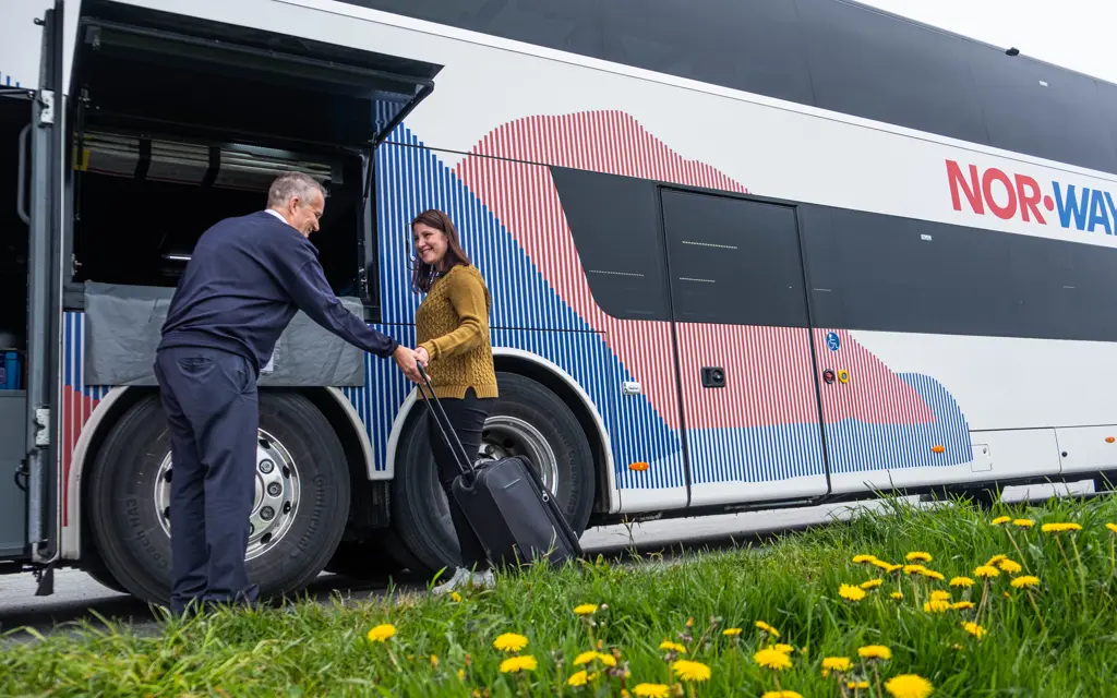 Passasjer leverer bagasjen sin til bussjåfør