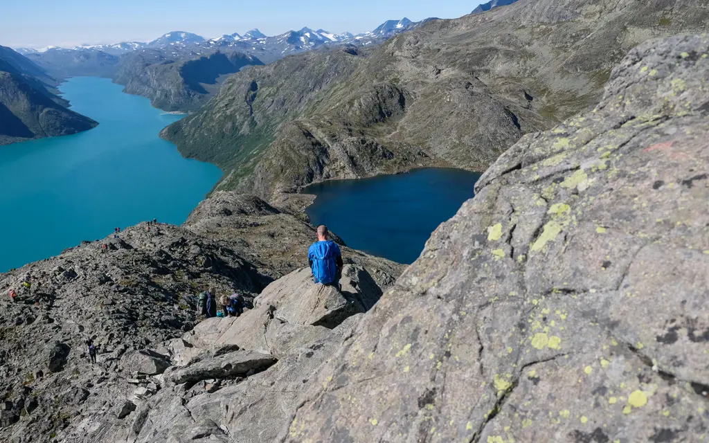 mann sitter med ryggen til kamera og ser utover utsikt fra besseggen