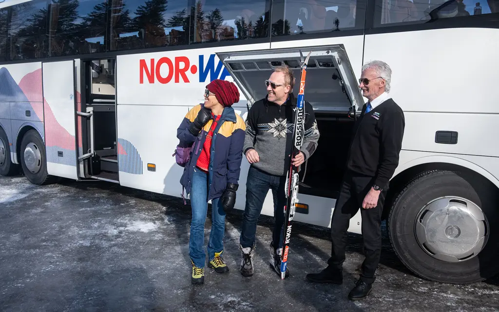 Travelers with skis outside a NOR-WAY bus
