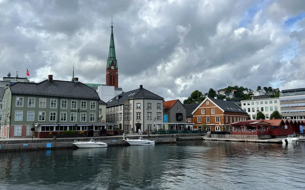 Bybebyggelse langs sjøkanten med båter i front i Arendal