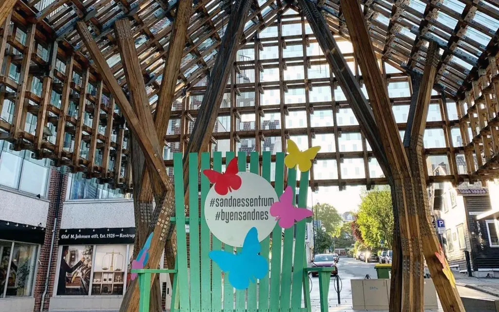 A large green wooden chair with a sign under a high tree-built roof.